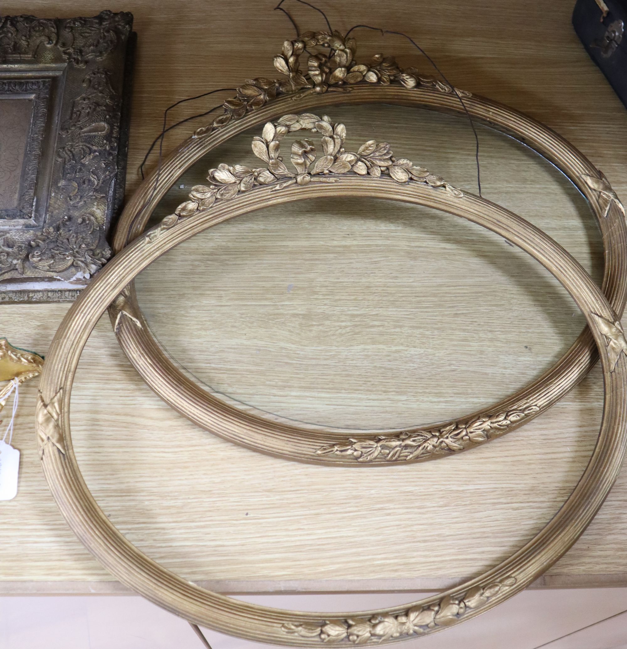 A pair of Victorian ornate gilt gesso oval picture frames, 50 x 55cm, a similar wall shelf and a picture